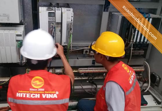 Hai kỹ thuật viên Hitech Vina kiểm tra tủ điều khiển tại nhà máy khách hàng